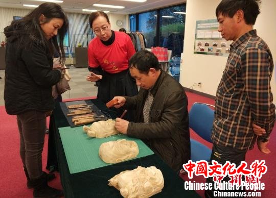 “中国民间工艺美术师”罗春明在现场还进行了傩面具雕刻及展示，引得市民驻足观看。　平懿 摄