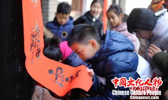 “孔府过大年”系列活动中设置了游客参与贴春联的环节。图为参与活动的小游客帮忙贴春联。 陈硕 摄 “孔府过大年”系列活动中设置了游客参与贴春联的环节。图为参与活动的小游客帮忙贴春联。 陈硕 摄