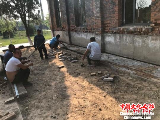 在A1展馆和A3展馆的连接处，50多岁的老师傅李金有正在对地面的旧砖块进行着替换处理，这里将在展览期间换上全新的地砖。平遥国际雕塑节组委会提供