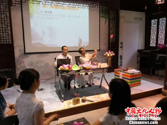 申文辉在古猗园教游人制作清仙纸莲花。 陈静 摄 申文辉在古猗园教游人制作清仙纸莲花。 陈静 摄